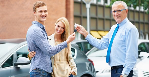Happy young couple receiving the keys to their new car